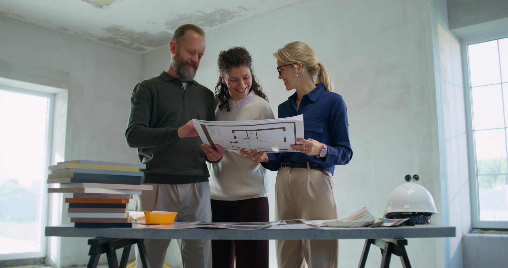 Bauherren und Planerin besprechen Grundriss und Projektunterlagen